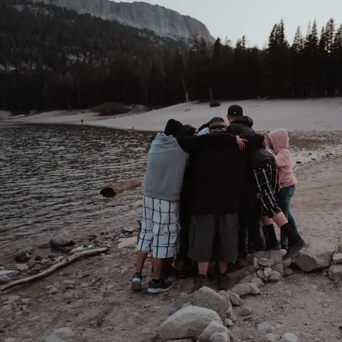 A group embracing beside a lake.